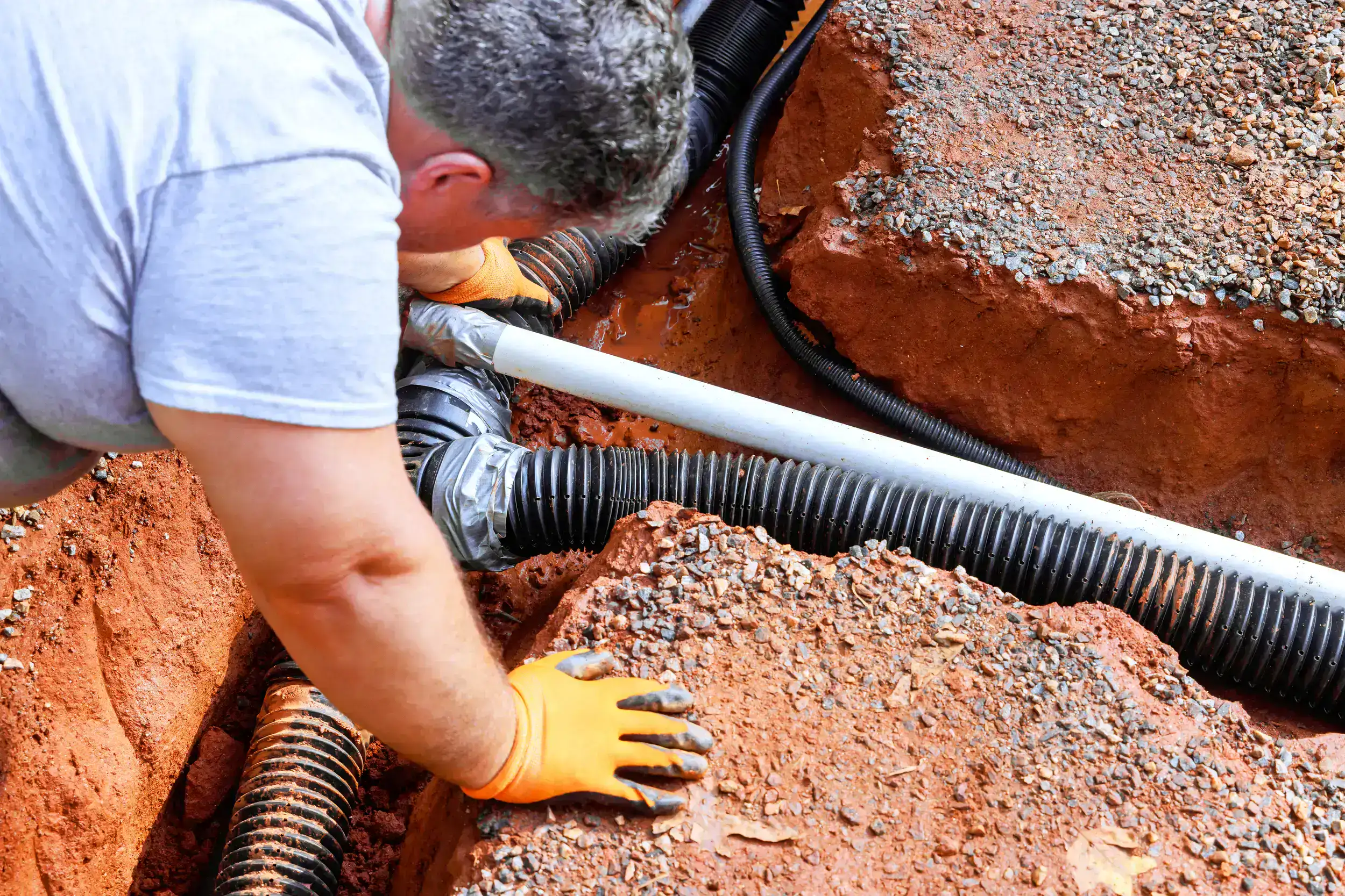 Laying the plastic pipes underground by the worker.